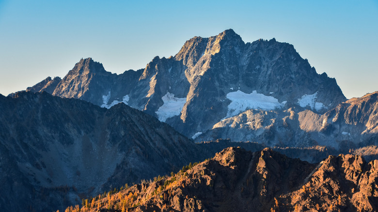 The sunrise reflects on tall granite peaks with pockets of snow in some places.