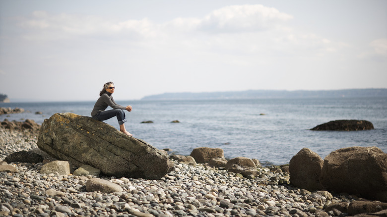 A man sits on a rock at a waterfront park in Freeland, WA