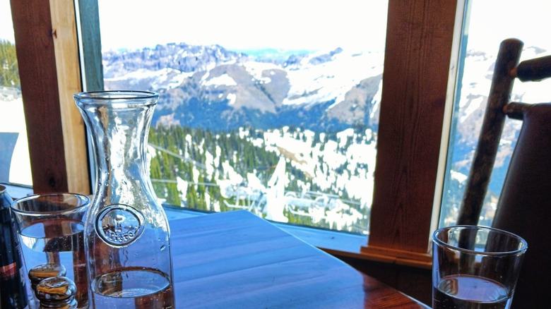 View of snowy mountains and trees from indoor restaurant table