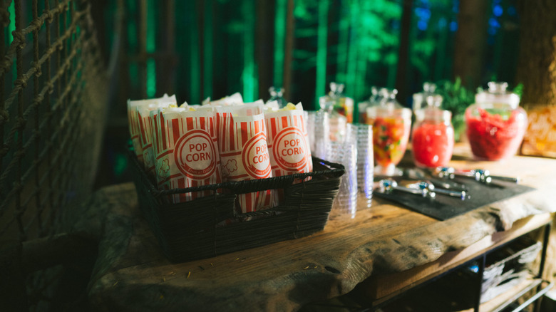 Bags of popcorn and jars of candy on a wooden table at the concession stand at The Emerald Forest, an outdoor event space in Redmond, Washington, U.S.A.