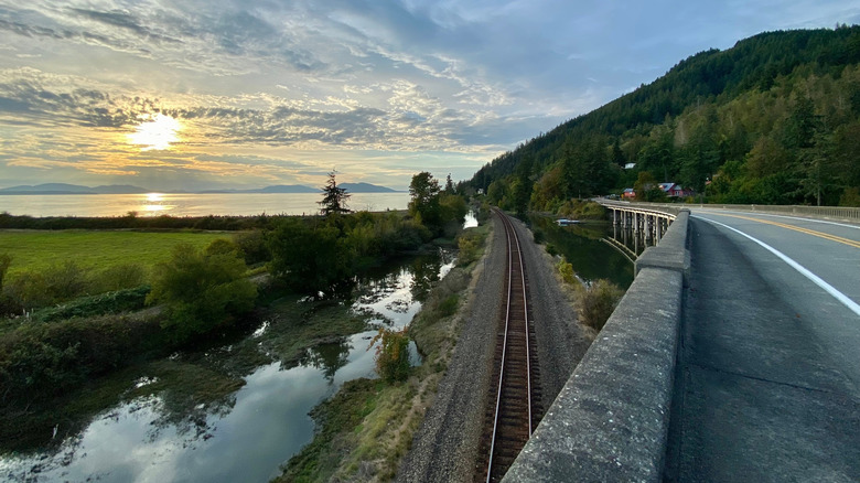 A bridge and railroad tracks recede into a low sun near the entrance of Larrabee State Park, Washington State