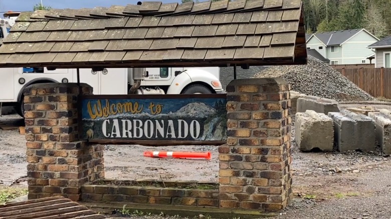 Brick sign reads "Welcome to Carbonado"