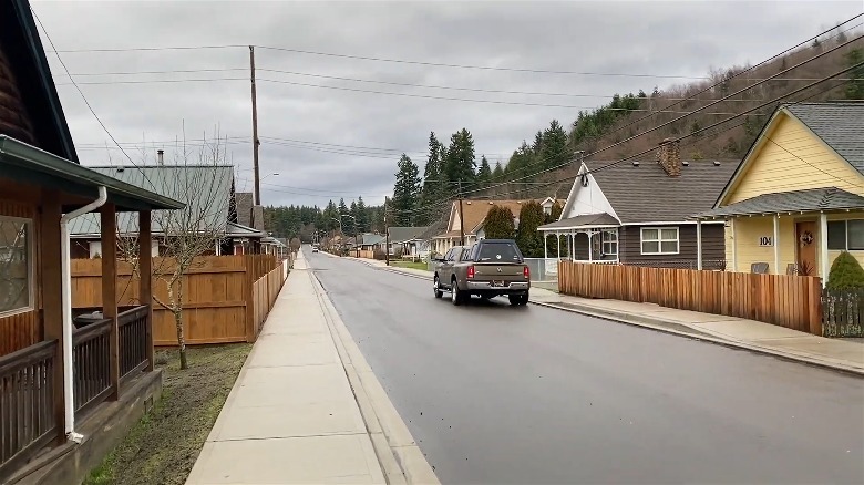 Buildings line a wet pavement street during overcast weather in Carbonado