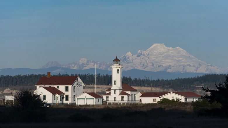 Point Wilson Lighthouse and buildings at Fort Worden, with forest and mountains behind