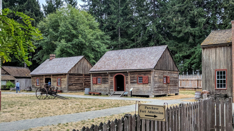 Old log buildings among evergreens at Fort Nisqually in Washington