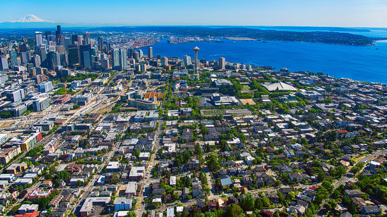 A wide aerial view of Downtown Seattle and its surrounding suburbs across the lakes and islands.