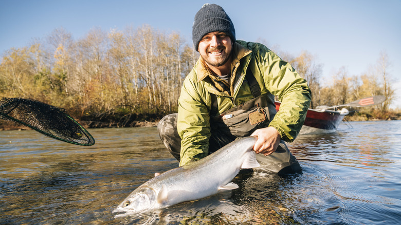 A man holds a steelhead he just caught in a river in Washington State