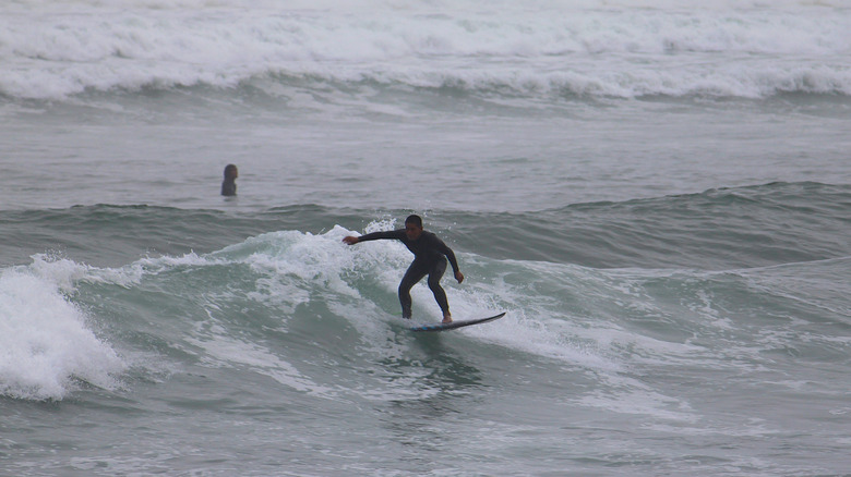 Surfer riding a wave on a gray, stormy day