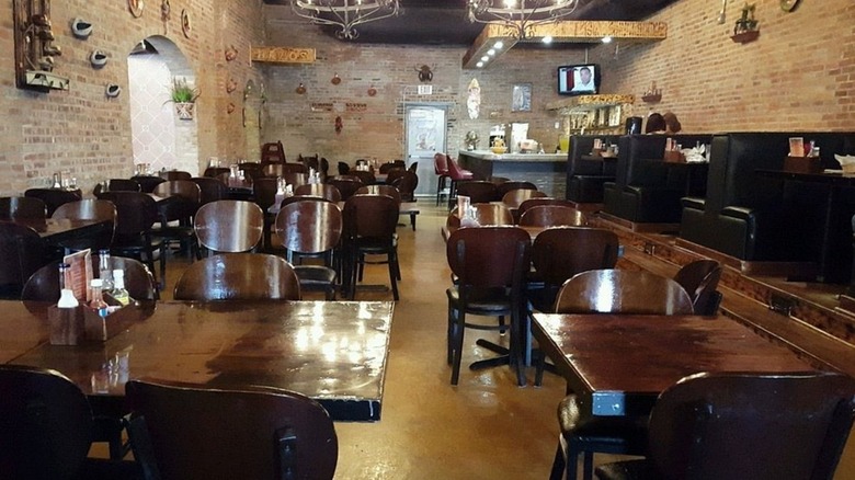 Interior of La Potosina Mexican restaurant, with dark wood tables and chairs surrounded by brick walls.