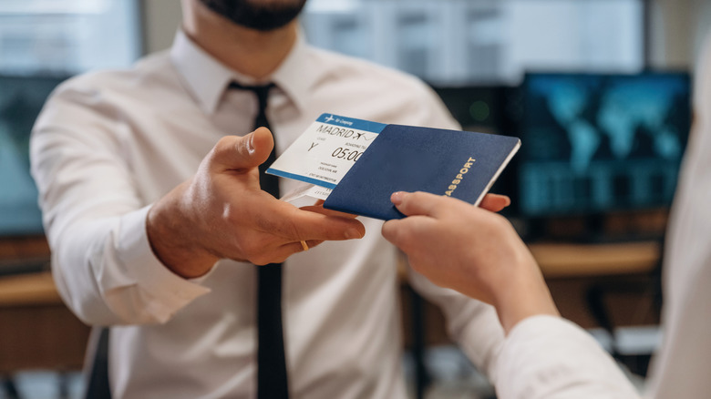 traveler hands over passport with boarding pass with madrid written on it