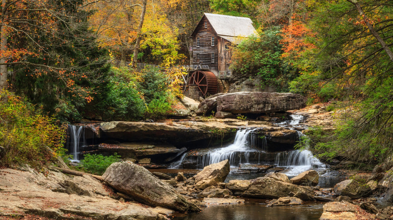 A waterfall cascading down rocks with wooden house in back