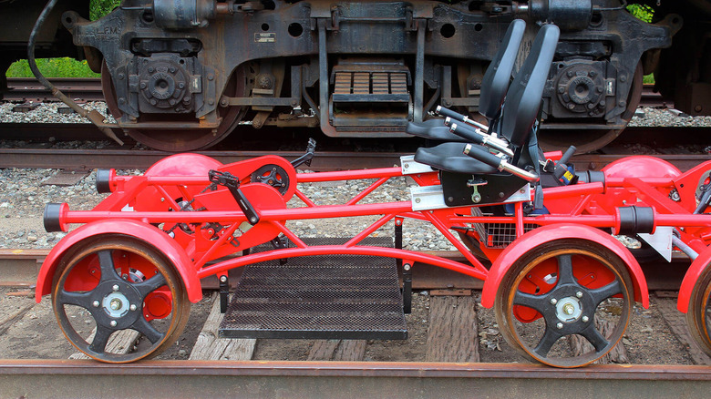 A Rail Explorer vehicle on a railroad track next to a train