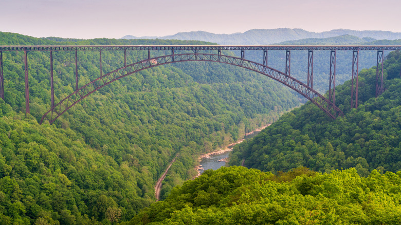 Brown bridge over New River Gorge, surrounded by green hills