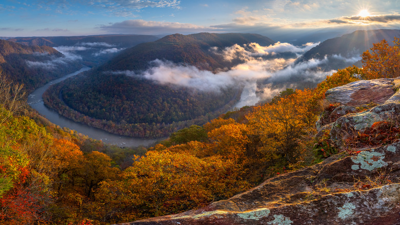 The morning sun lights up the fog and autumn foliage hanging above the New River Gorge National Park in West Virginia.