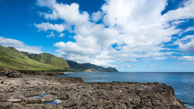 Volcanic rock, green mountains by ocean