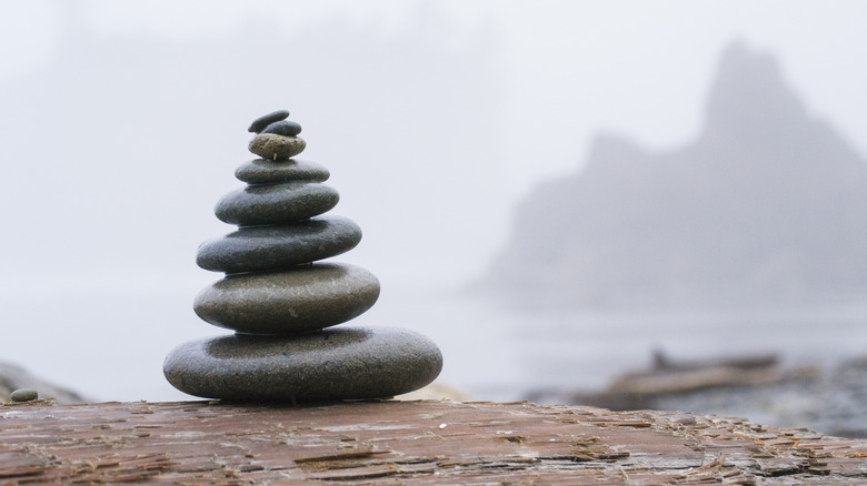 A tower of smooth stones stands in front of a foggy seascape in Washington State