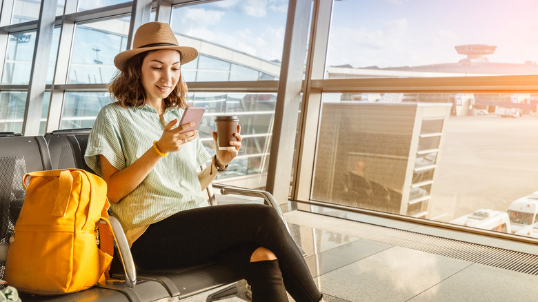 Woman with a hat and yellow backpack waiting at her gate in the airport