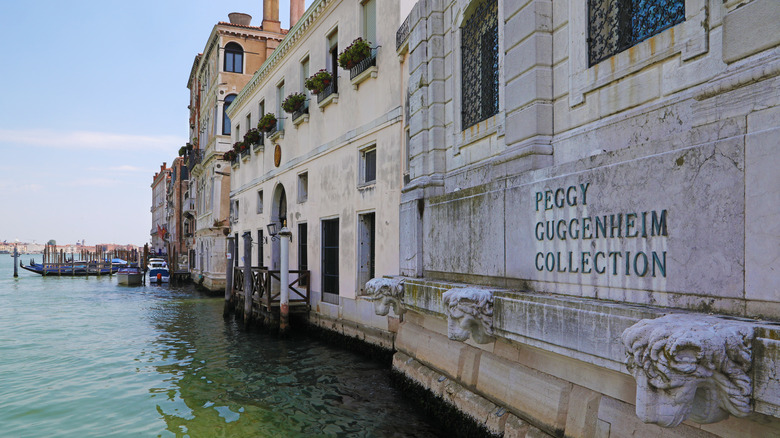 The front of the Peggy Guggenheim Collection on the canal with neighboring buildings and parked boats