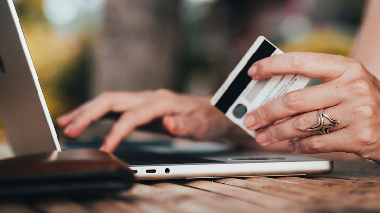 Person holding a credit card and using a computer
