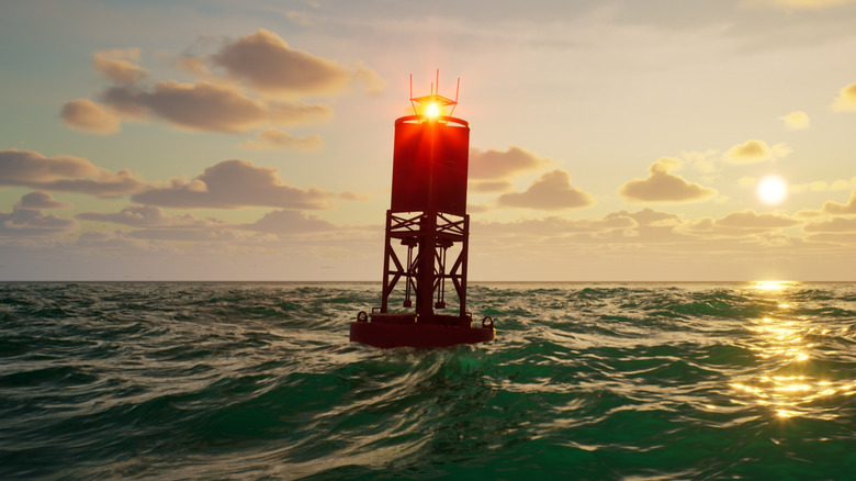 A shadowy buoy with a light on top floats on the water with the sun setting in the background