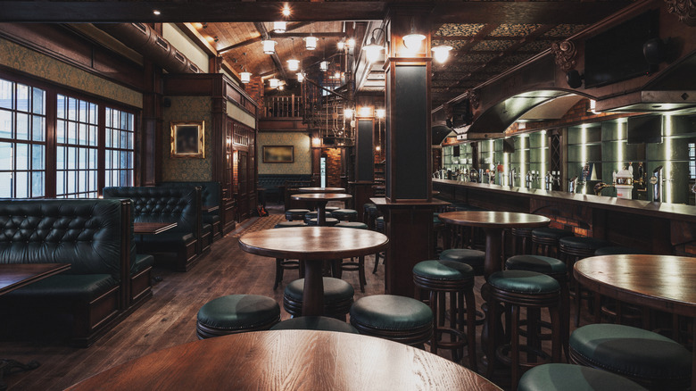 Interior of a brew pub with dark wood, leather furniture, and brewing tanks visible behind the bar