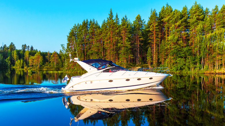 Yacht sailing across a lake with forested shores