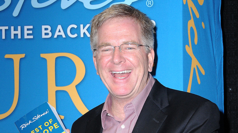 Travel writer Rick Steves smiles while holding one of his books