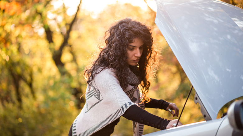 A woman checking the hood of her car