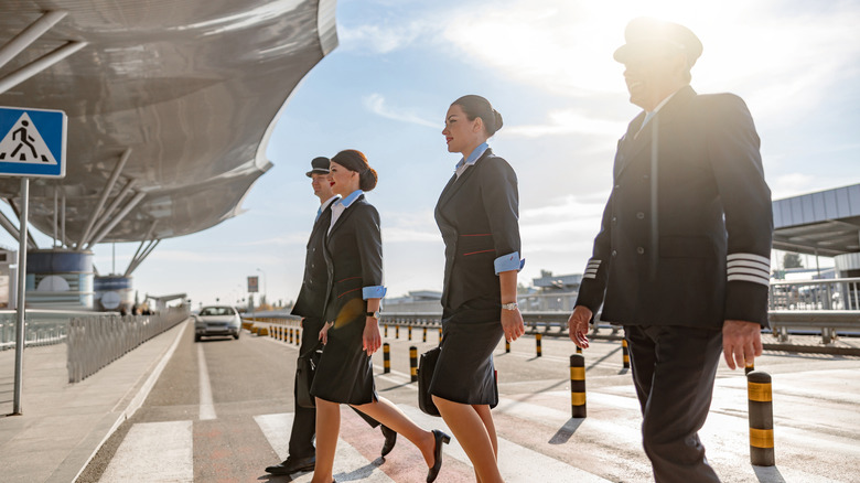 Captain and flight crew walking together across a lane at an airport
