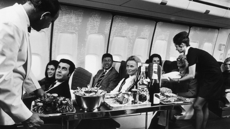 Black and white photo of flight attendants serving passengers