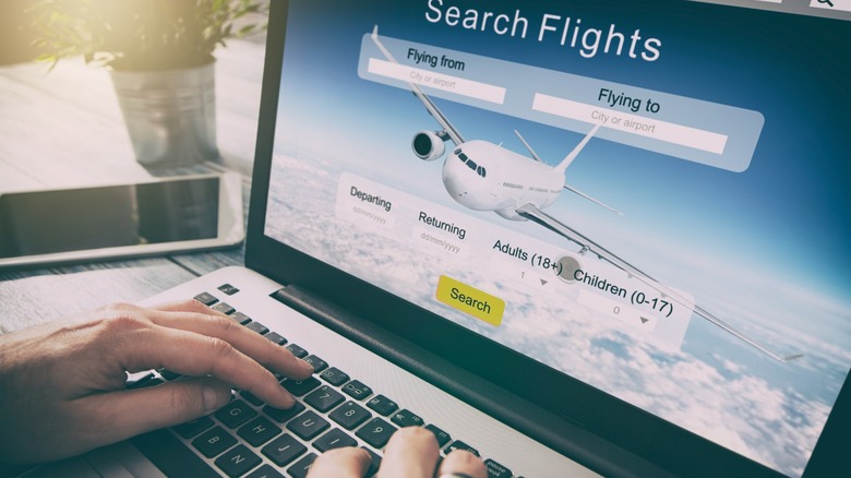 hands rest on computer open to flight comparison website