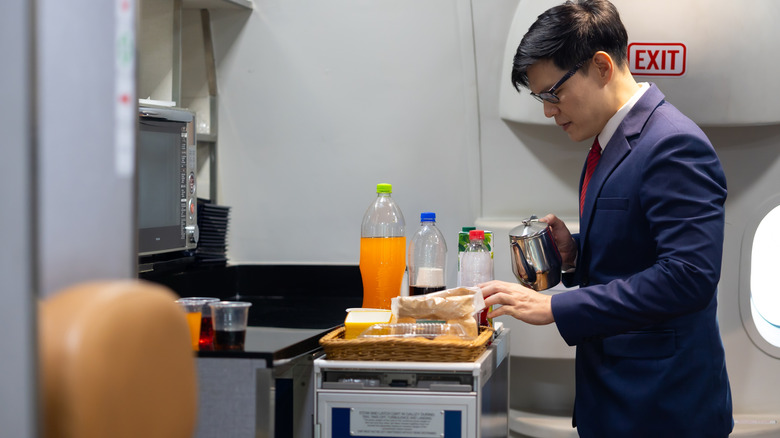Flight attendant holding water bottle in airplane cabin