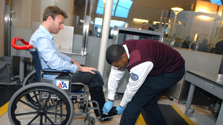 TSA agents swabbing the shoe of a passenger in a wheelchair