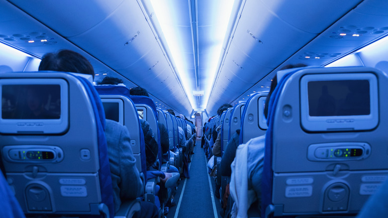 Inside of a dimly lit airplane with passengers seated