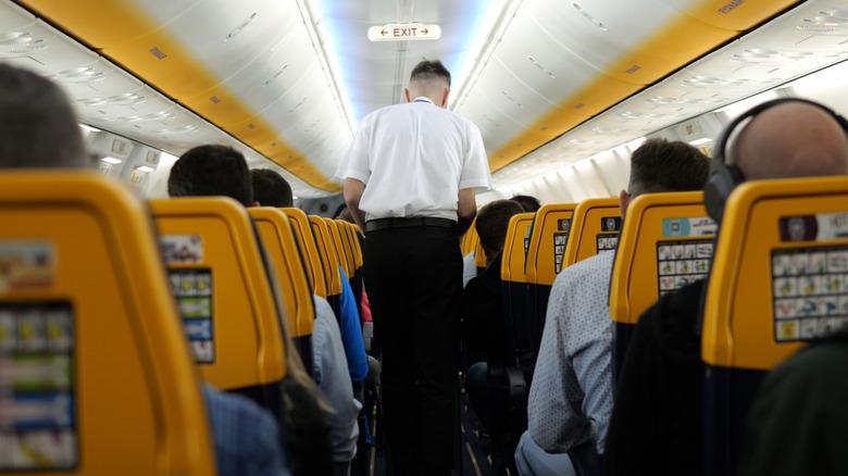 Flight attendant walking down plane aisle