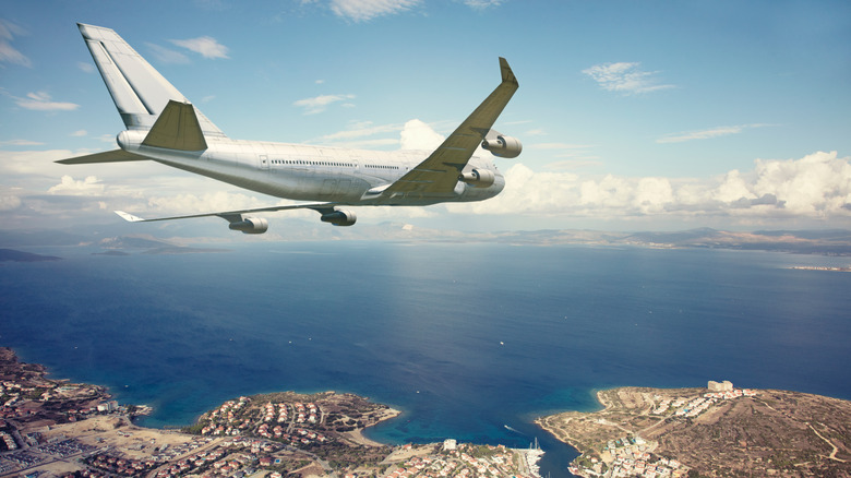 Airplane flying above a coastal city for landing