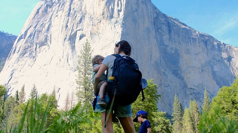 A woman hiking with two children with a view of Half Dome in Yosemite National Park.