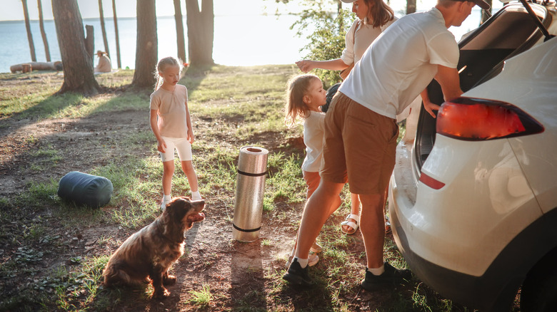 A family unpacking their vehicle at a campsite