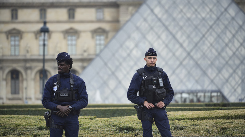 Two Paris police officers stand in front of the Louvre after the heist