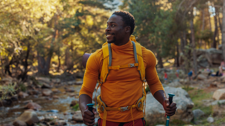 A backpacker in orange shirt hiking in the forest