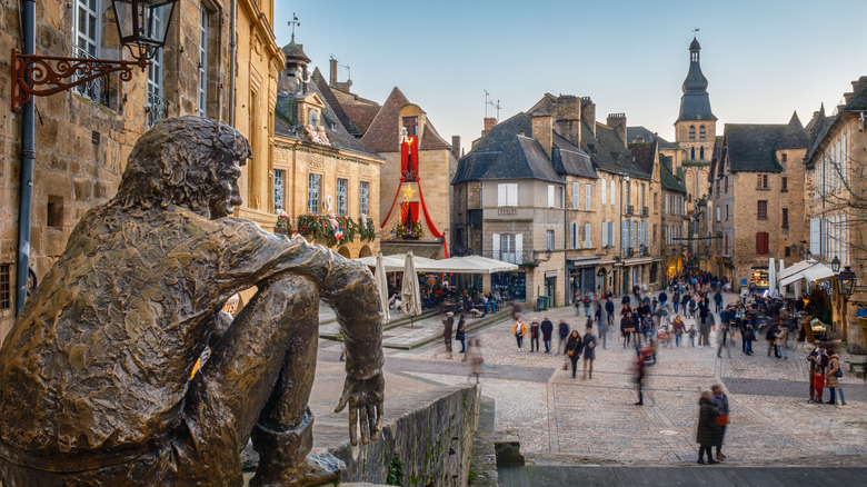 "Le Badaud" or Onlooker, a bronze sculpture by Gerard Auliac, watches over shoppers in the market square at Sarlat in the Dordogne region of France.
