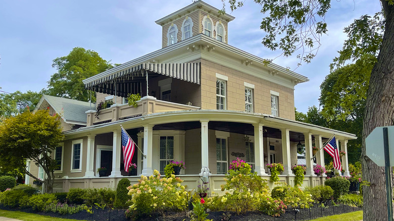 Historic building in Lewiston with flowers in yard and American flags