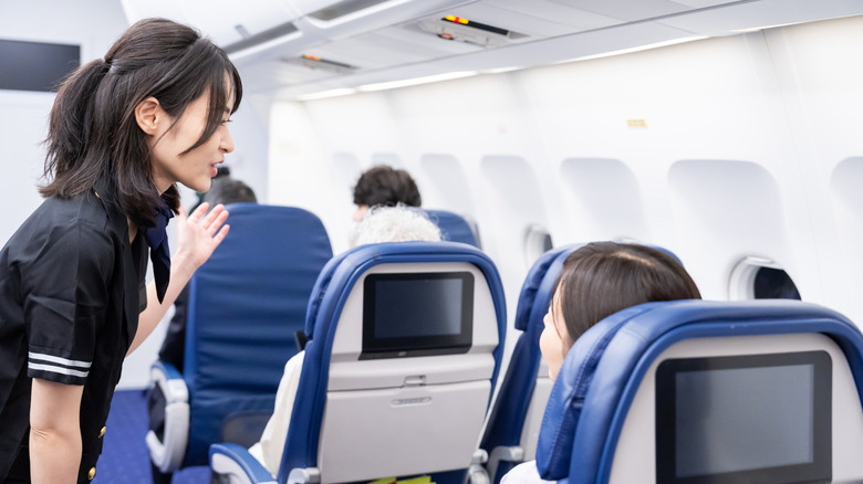 Flight attendant speaking with a passenger on a flight