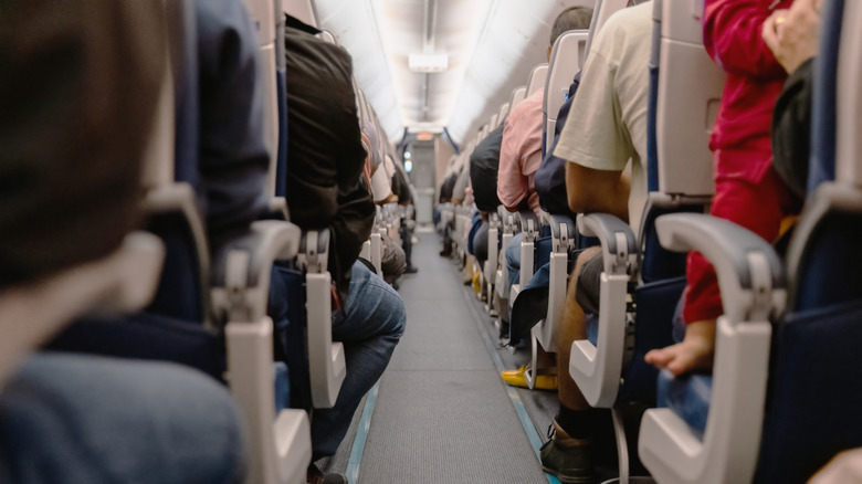 An aisle in a plane cabin with people sitting in their seats