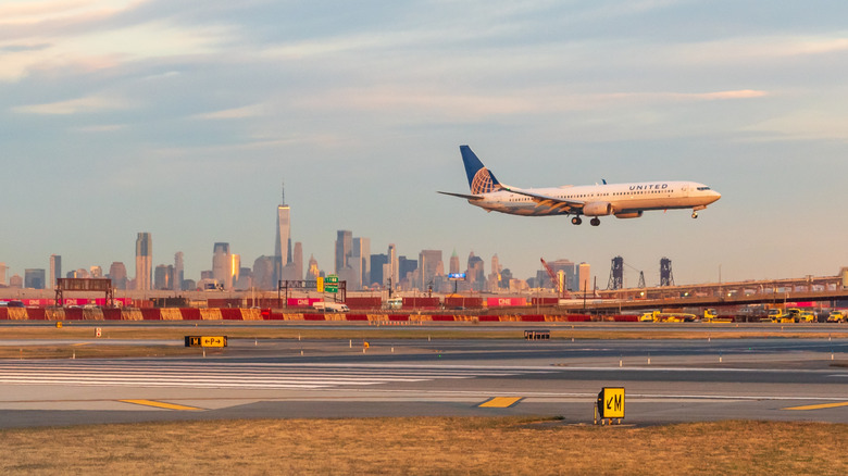 United Airlines jet landing at Newark Liberty Airport at golden hour with the Lower Manhattan skyline in the background