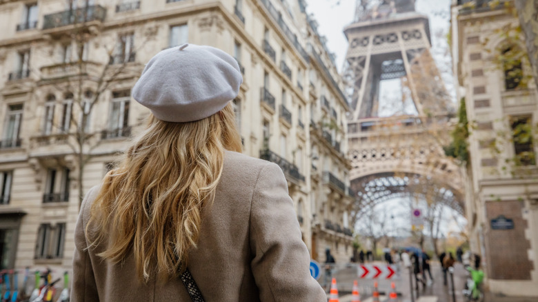 A woman walks through the streets of Paris near the Eiffel Tower