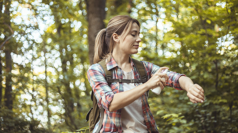 Woman applies bug repellent in forest
