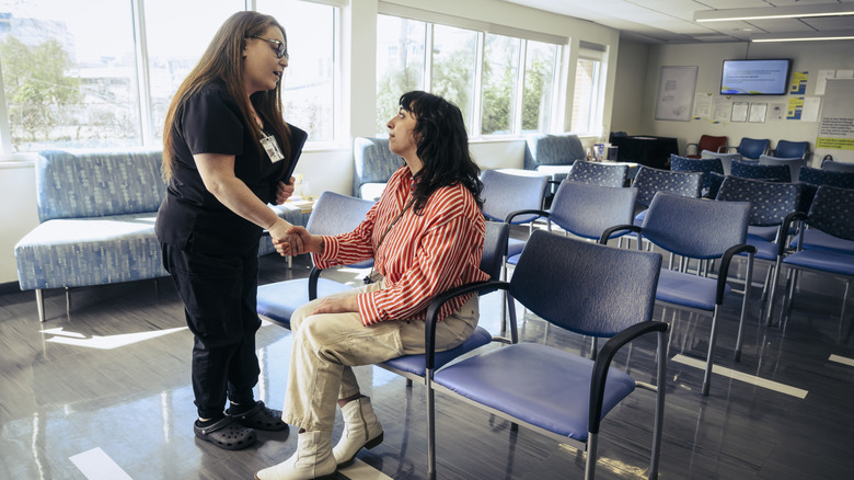 A female patient shaking hands with a doctor in a hospital waiting room.
