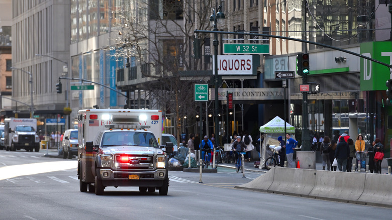 An ambulance driving through New York City with its lights on.