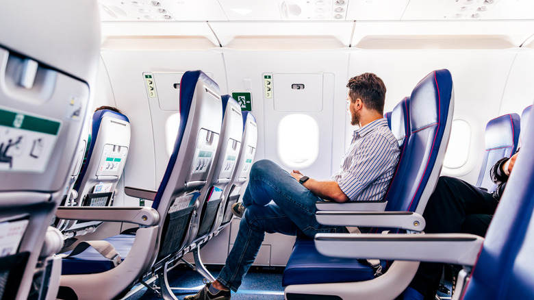 A man sits in a seat on an airplane looking out the window
